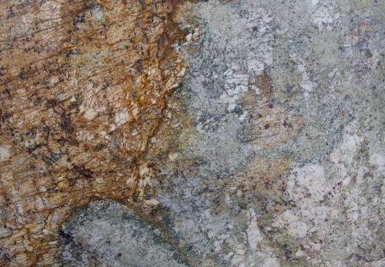 Texturierte Gesteinsoberfläche mit orangefarbenen und grauen Flecken.